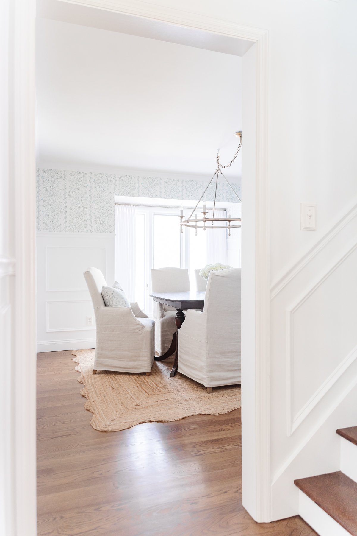 A dining room with white table and chairs featuring pinch pleat drapes.