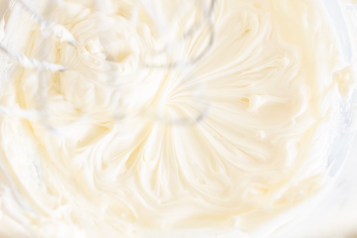 Whipped cream cheese being prepared in a bowl.