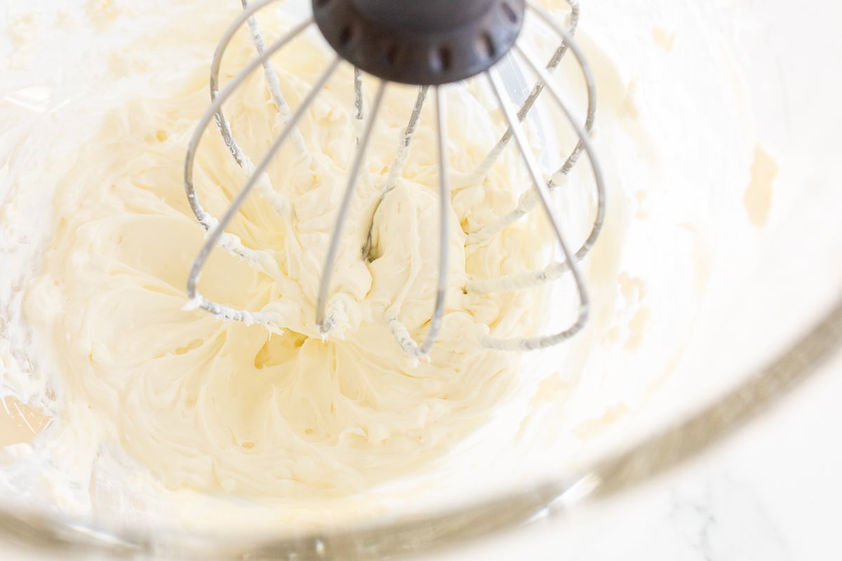 Whipped cream cheese being prepared in a bowl.