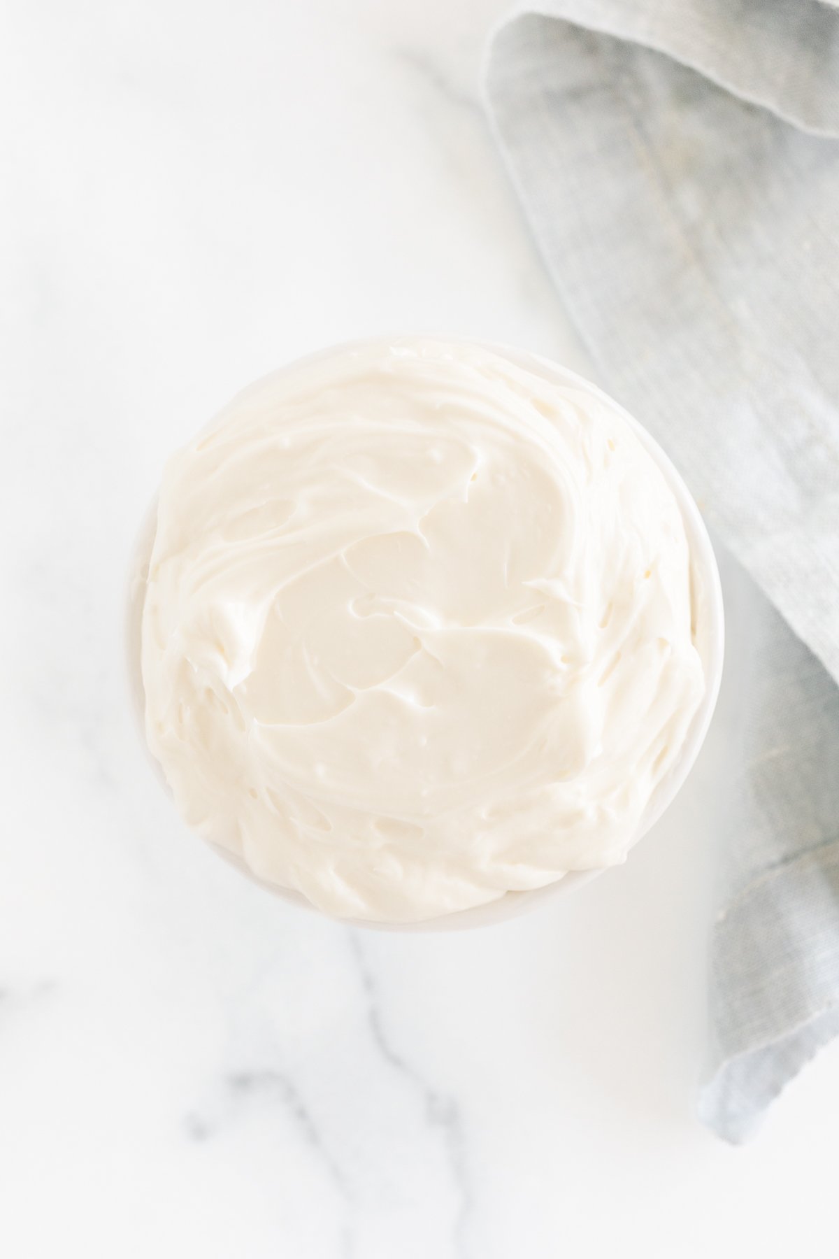 Whipped cream cheese in a bowl on a marble table.