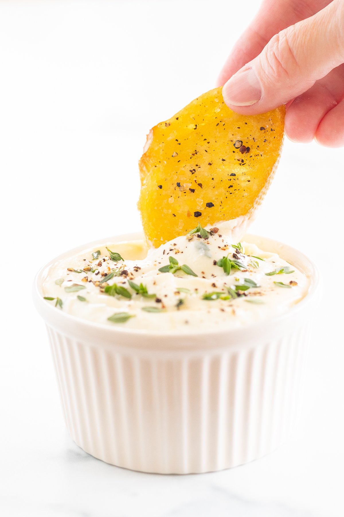 A person dipping a chip into a bowl of dip.