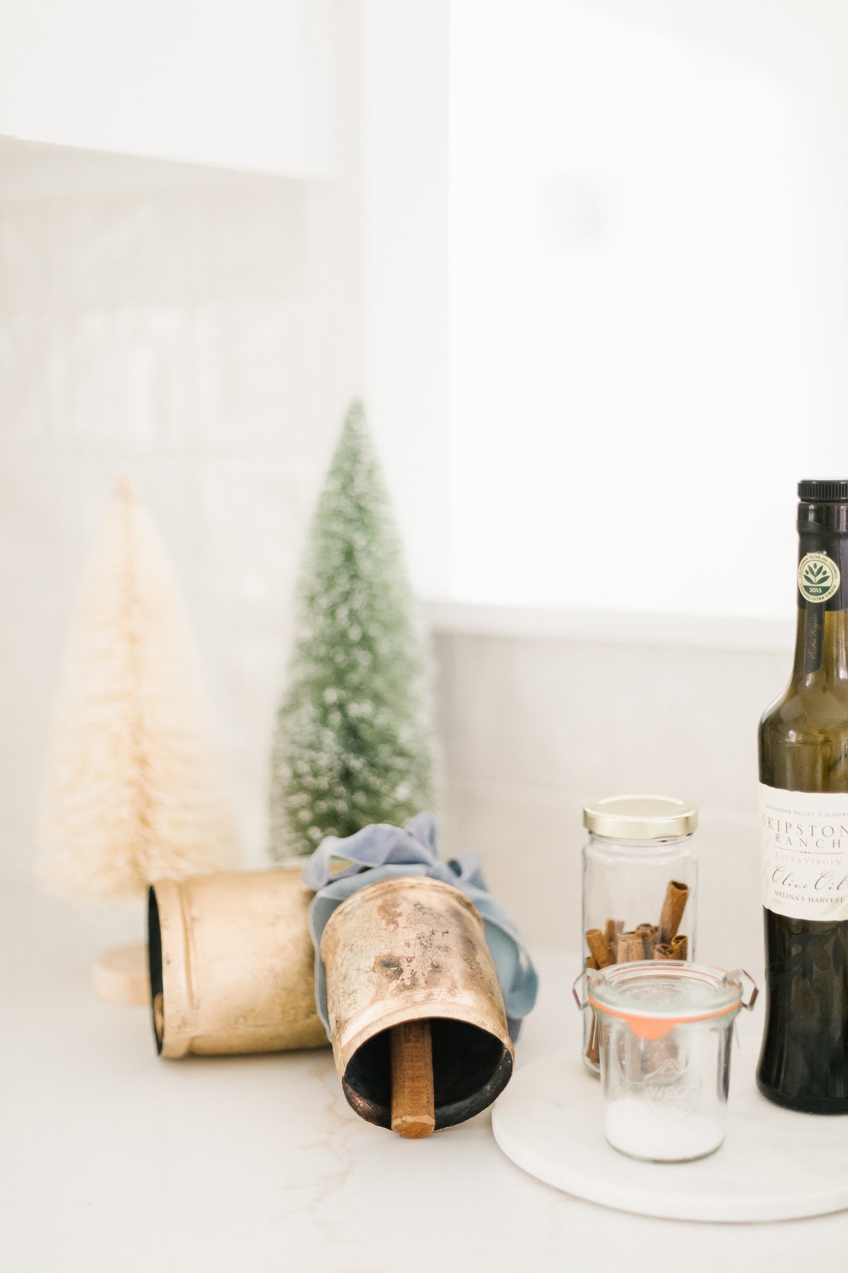 A bottle of olive oil in a christmas scene with small gold bells.