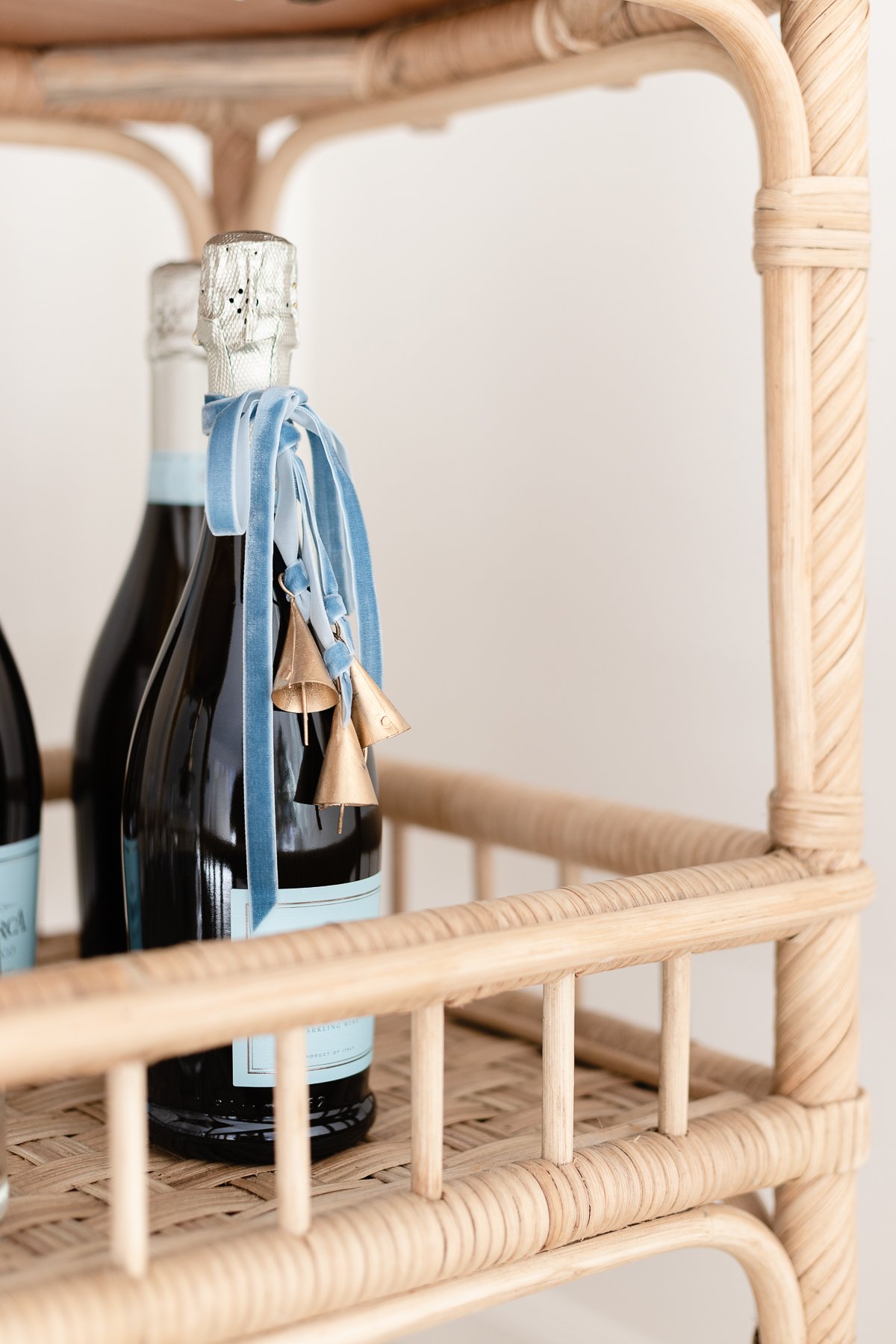 Two bottles of champagne on a rattan bar cart.