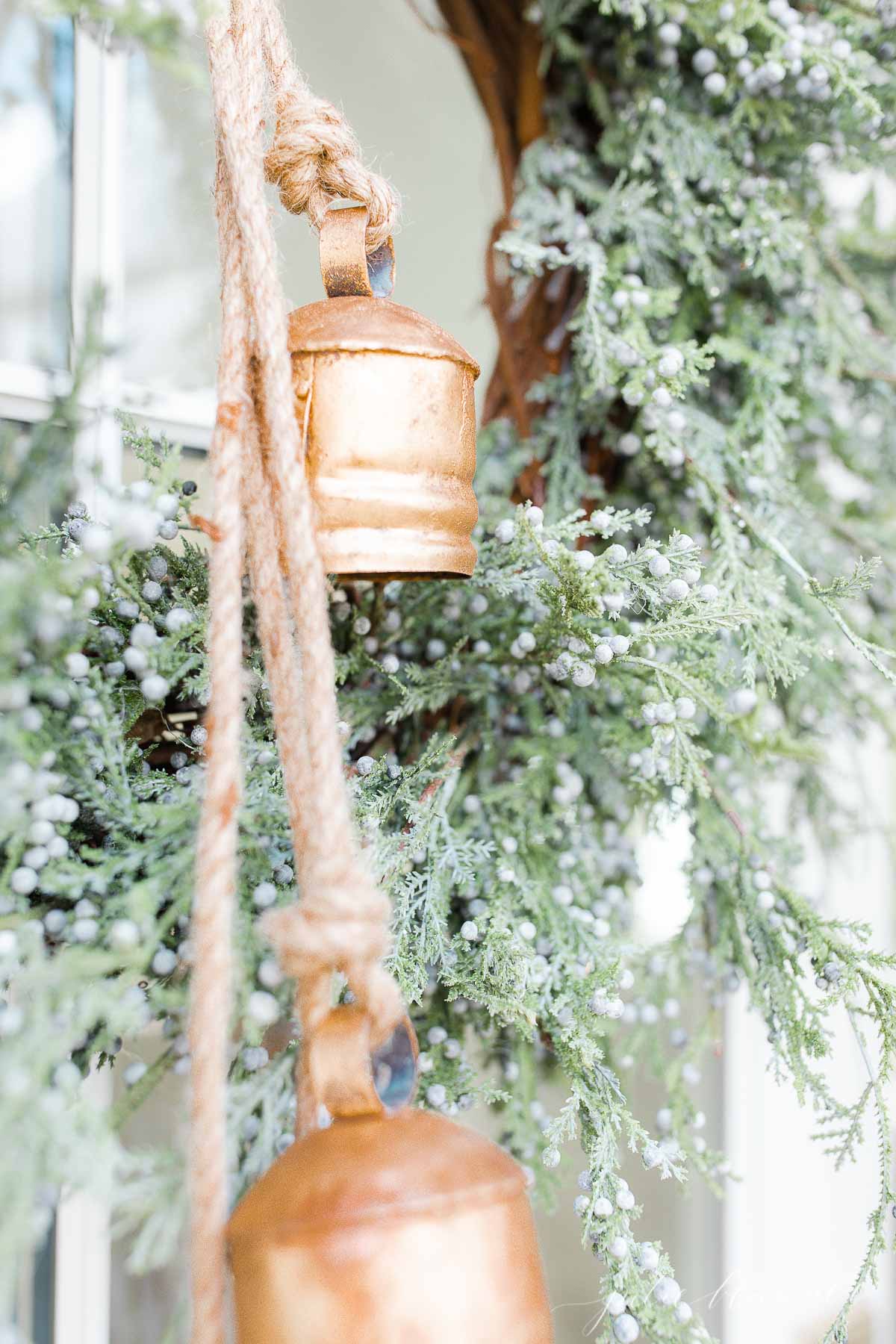 Bells hanging from a wreath on a front porch.