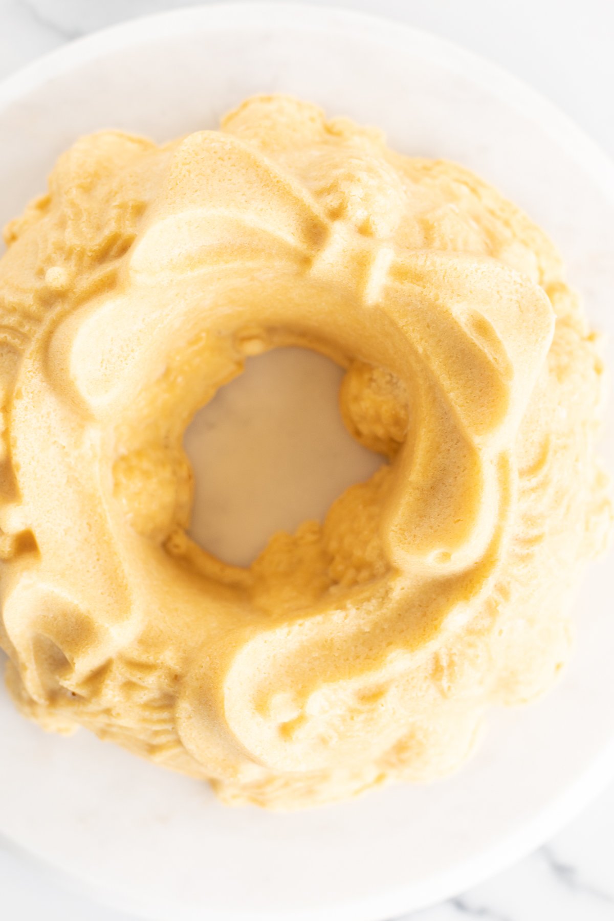 A yellow cake on a white plate with a bow on it, perfect for Christmas celebrations.