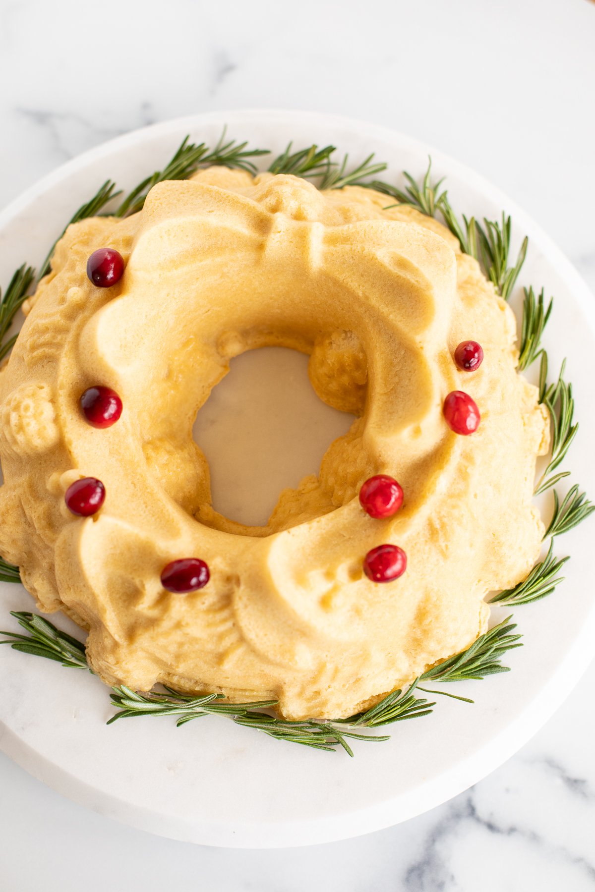 A Christmas wreath adorned with cranberries and sprigs of rosemary.