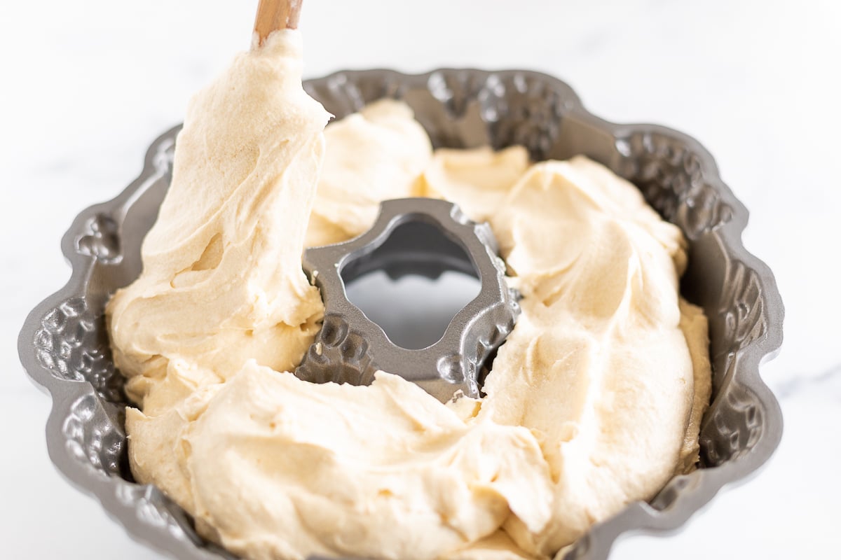 Whipped cream being poured into a muffin tin for a Christmas Bundt Cake.