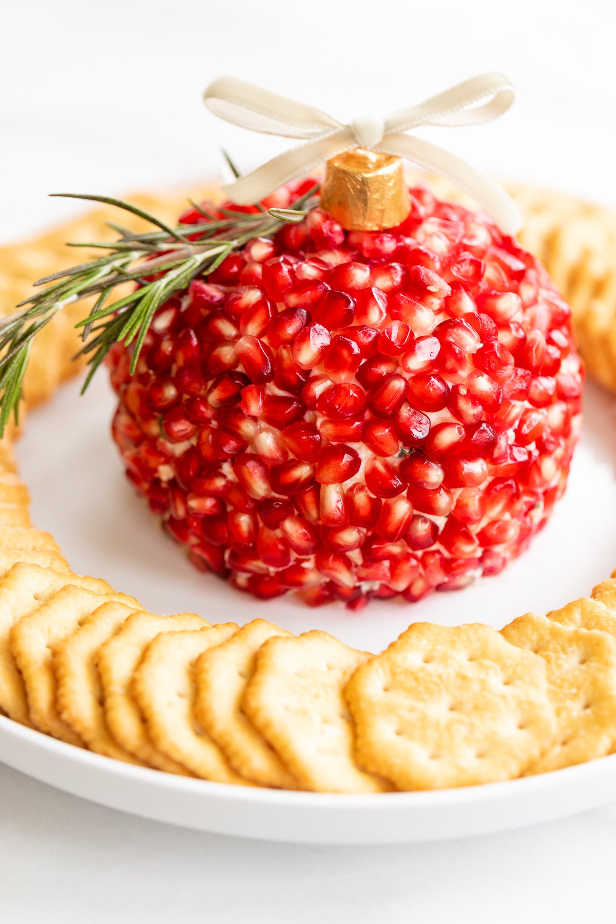 A plate with crackers and a pomegranate Christmas cheese ball.