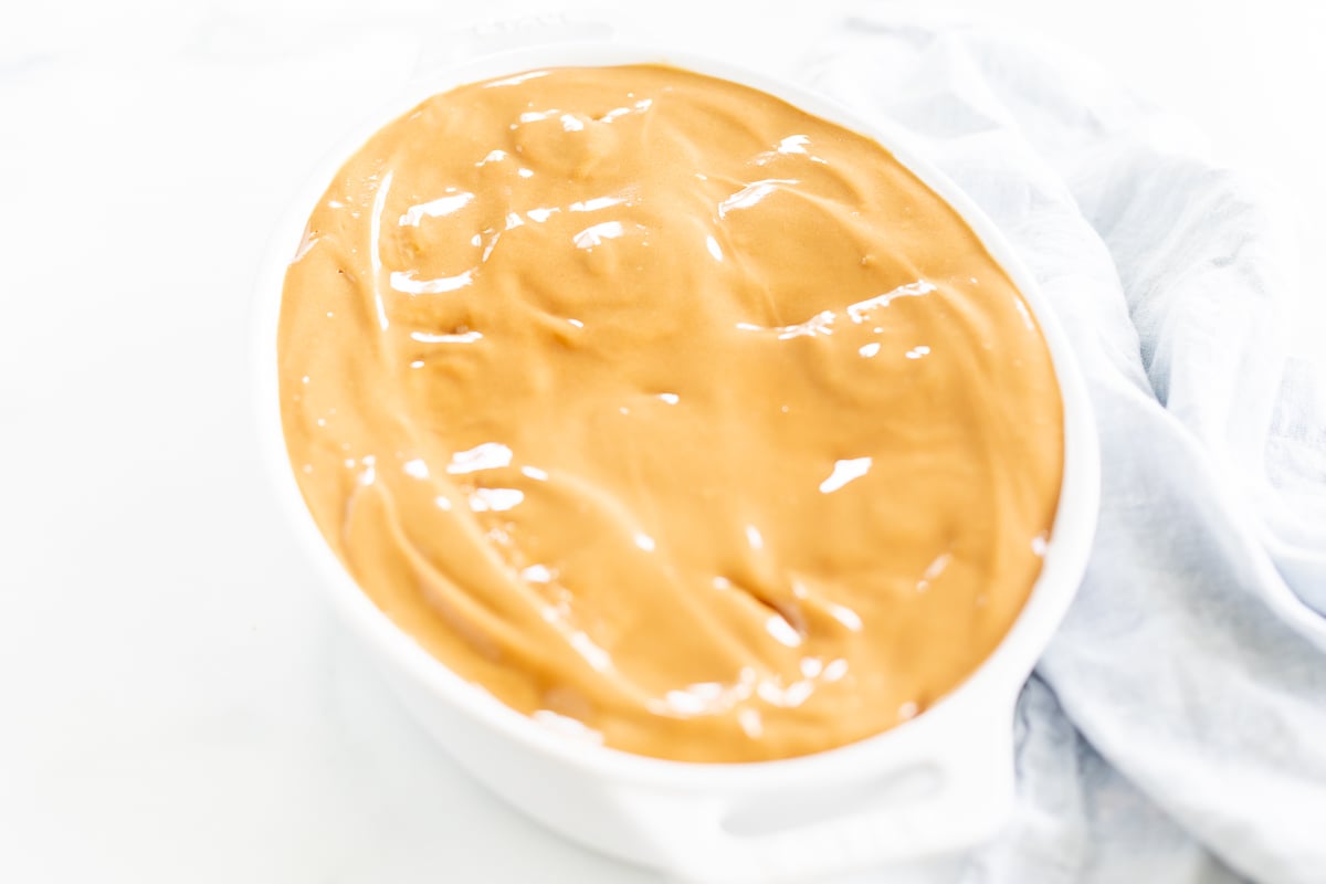 Peanut butter in a white bowl decorated with Cookie Butter Cinnamon Rolls.