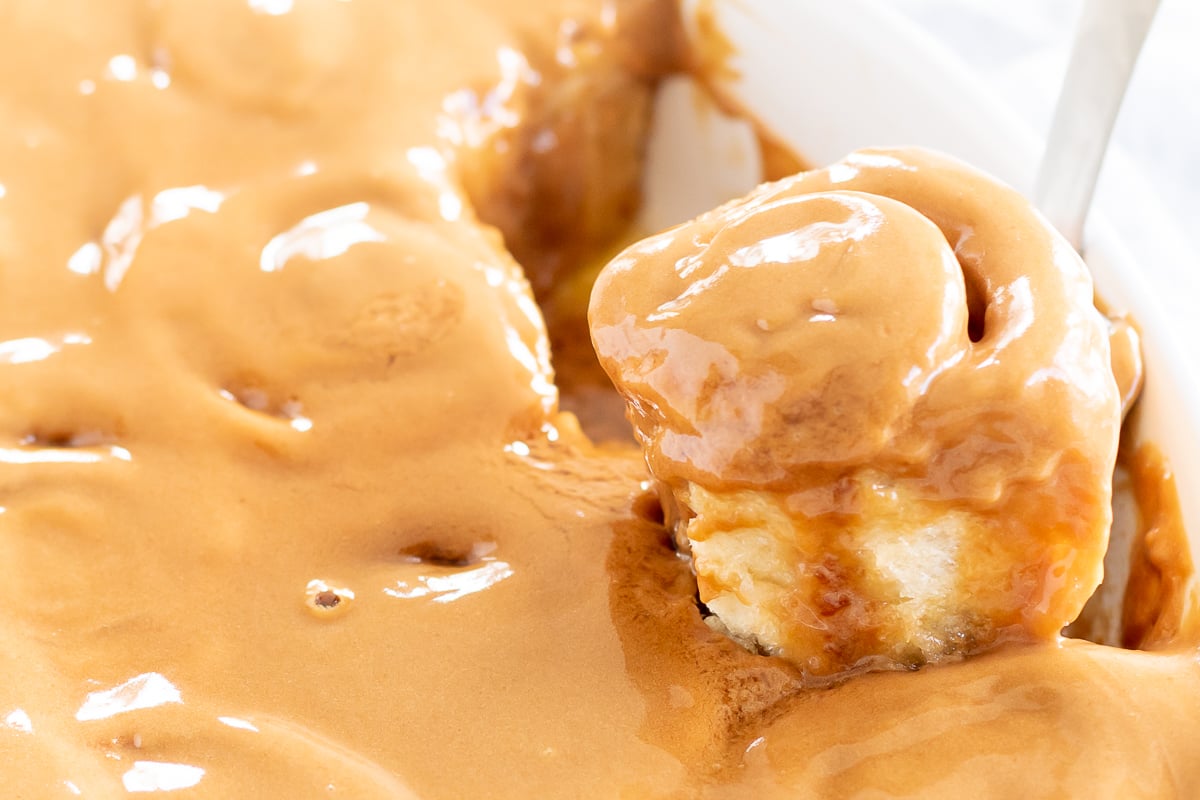 Cookie Butter Cinnamon Rolls topped with a spoonful of peanut butter in a white bowl.