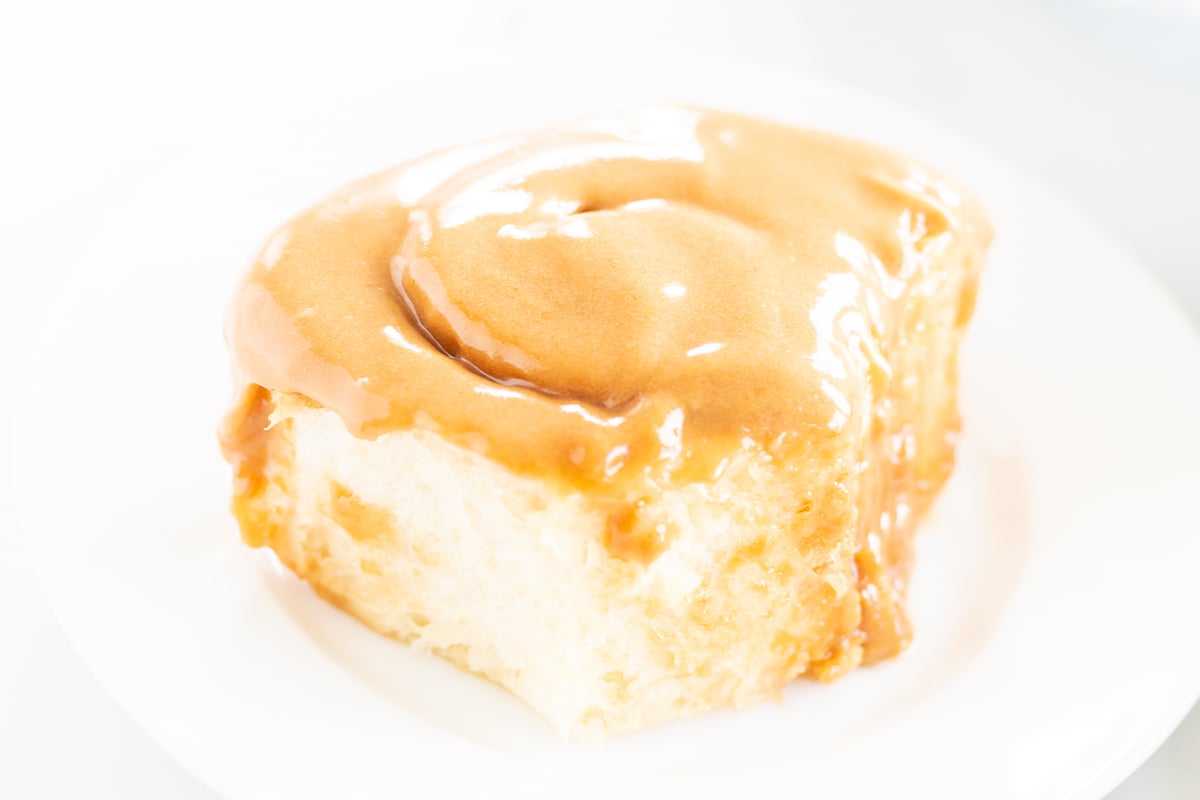 A Cookie Butter Cinnamon Roll on a plate, accompanied by a fork.