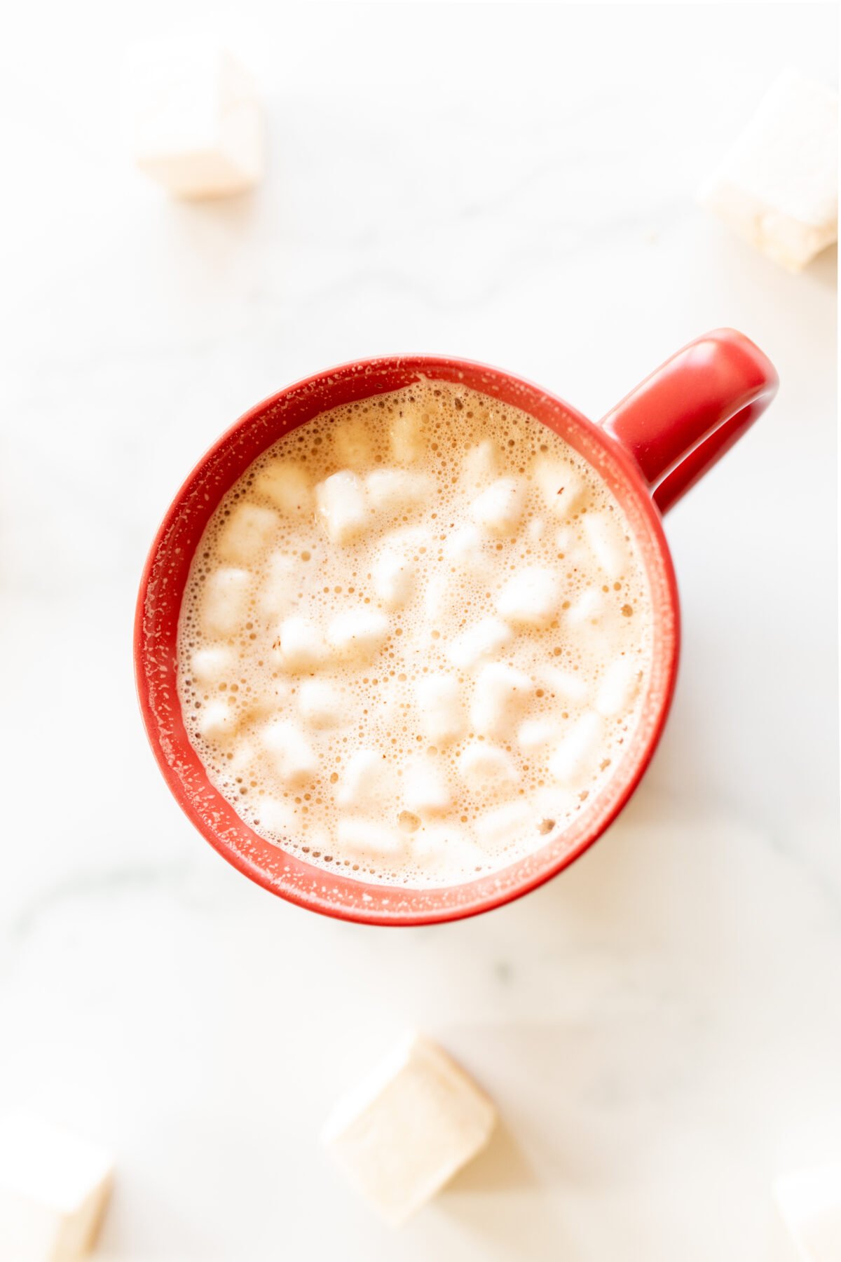 Dark hot chocolate bombs in a red mug with marshmallows.