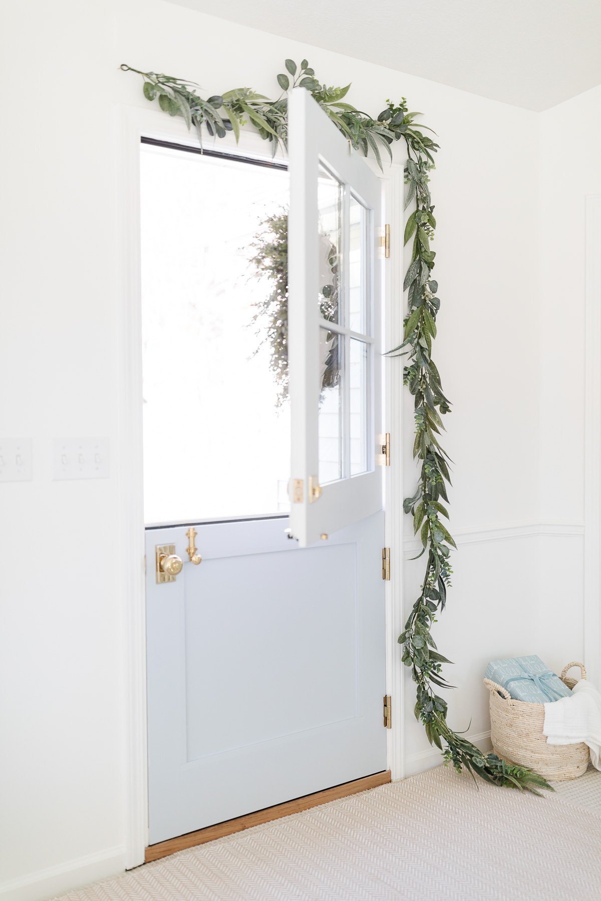 A white door with a green garland on it.