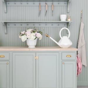 A green kitchen with shelves and a watering can.