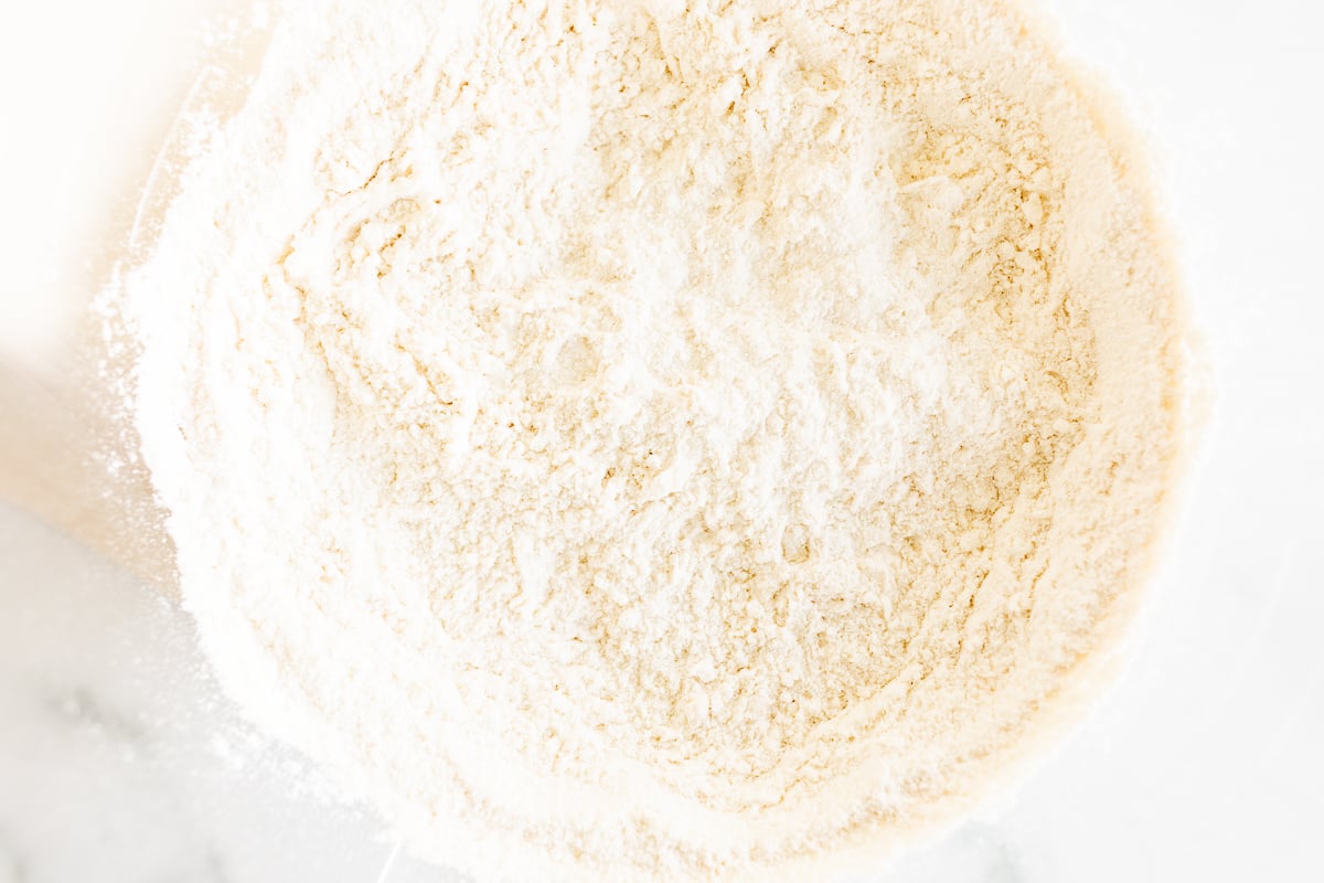 A bowl of flour next to a bowl of Cookie Butter Cinnamon Rolls.