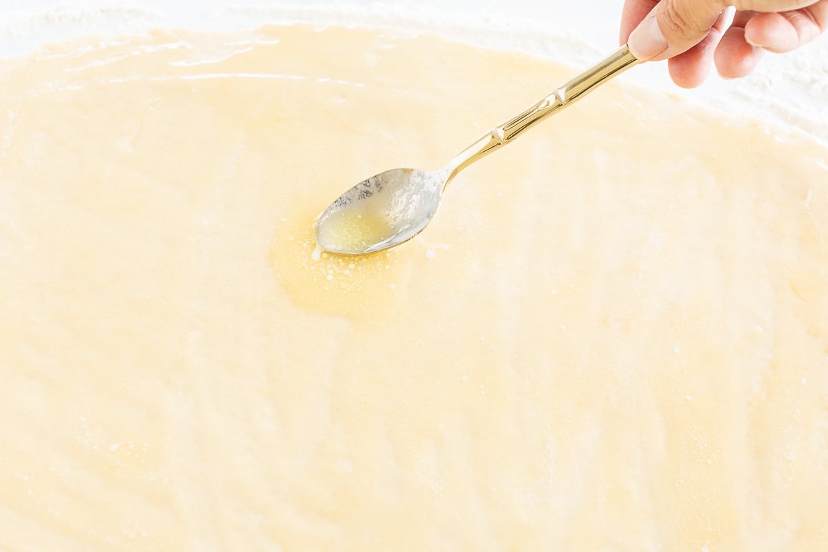 A person is dipping a spoon into a bowl of Cookie Butter batter.