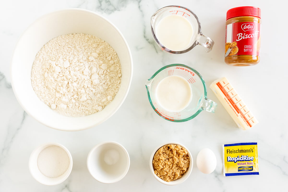 The ingredients for cookie butter cinnamon rolls are laid out on a marble table.