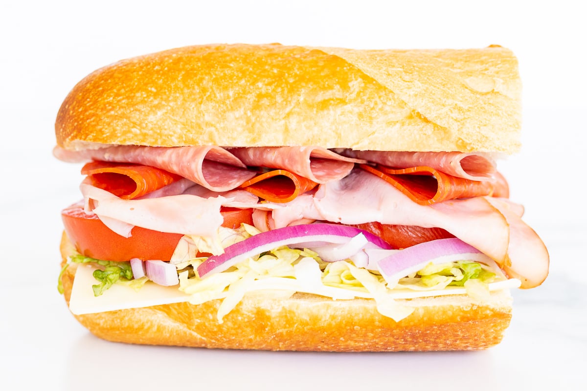 An Italian BMT sandwich with deli meat, lettuce, tomatoes, and onions.