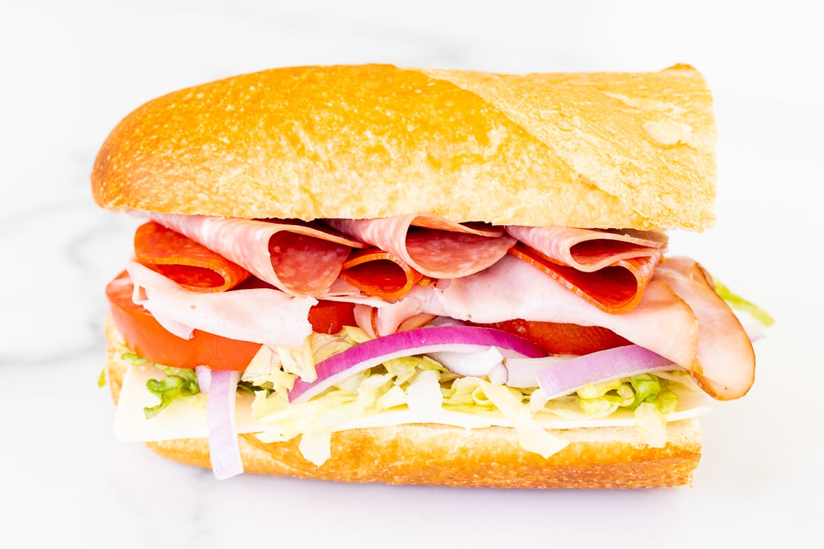 An Italian BMT sandwich with deli meat, lettuce, tomatoes, and onions.