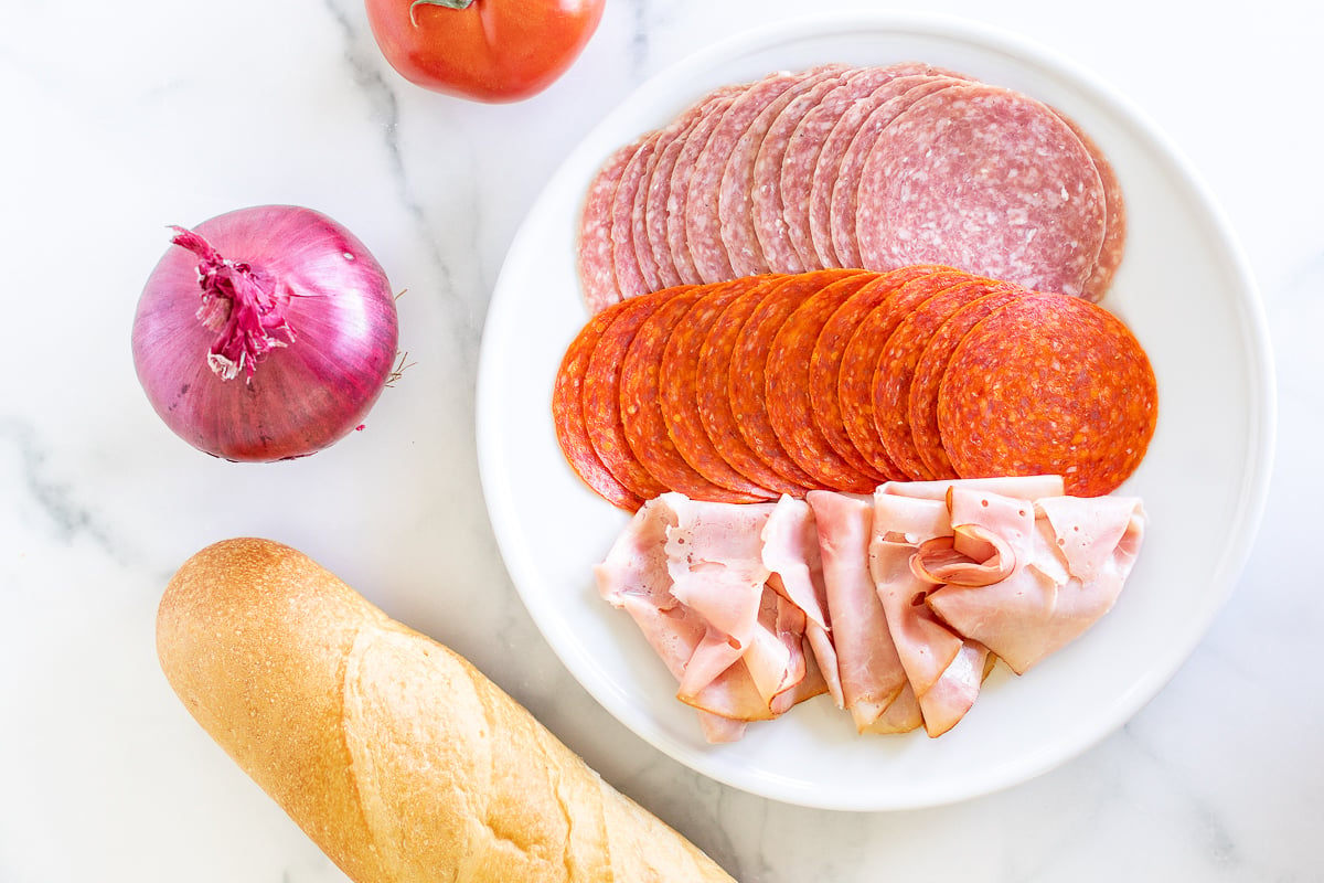 A plate of meat, bread and vegetables on a marble table.