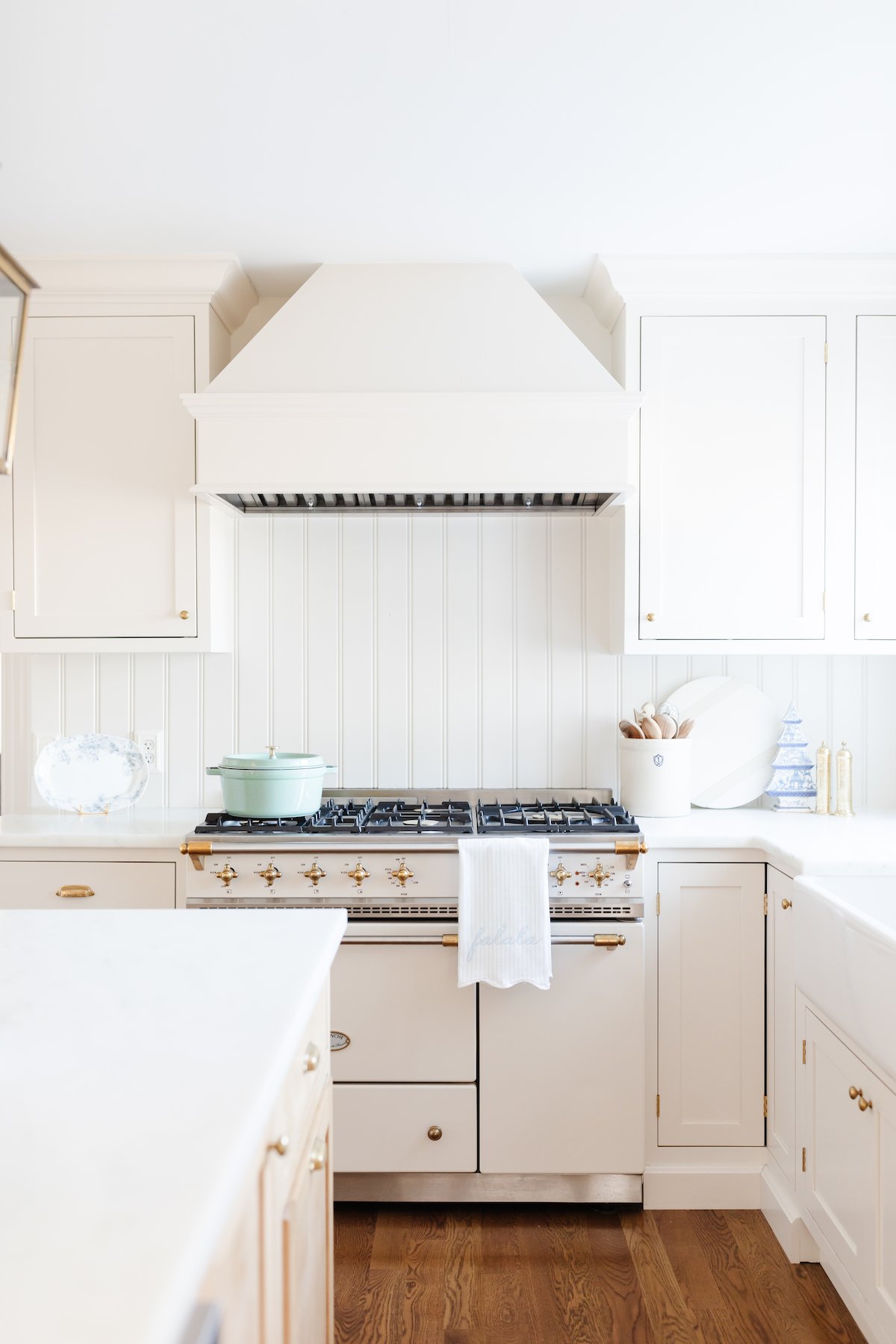 A white kitchen with wood floors and a stove, perfect for finding unique kitchen gifts.