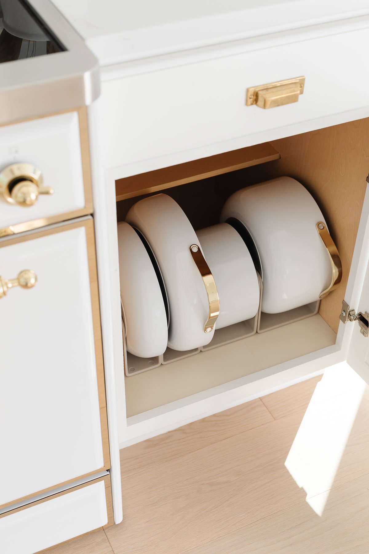 A kitchen with a white cabinet and a set of pots and pans, perfect for kitchen gifts.