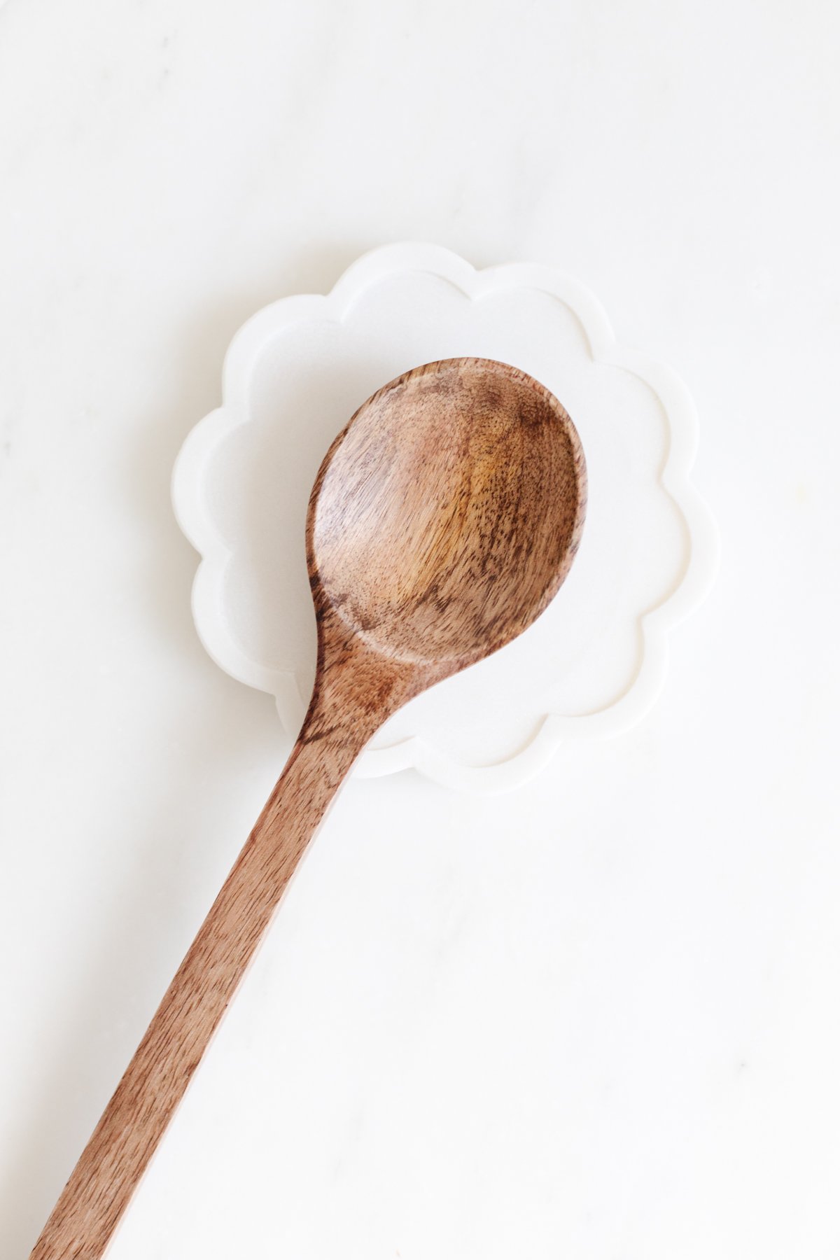 A wooden spoon, a perfect addition to any kitchen, sits on a white plate.