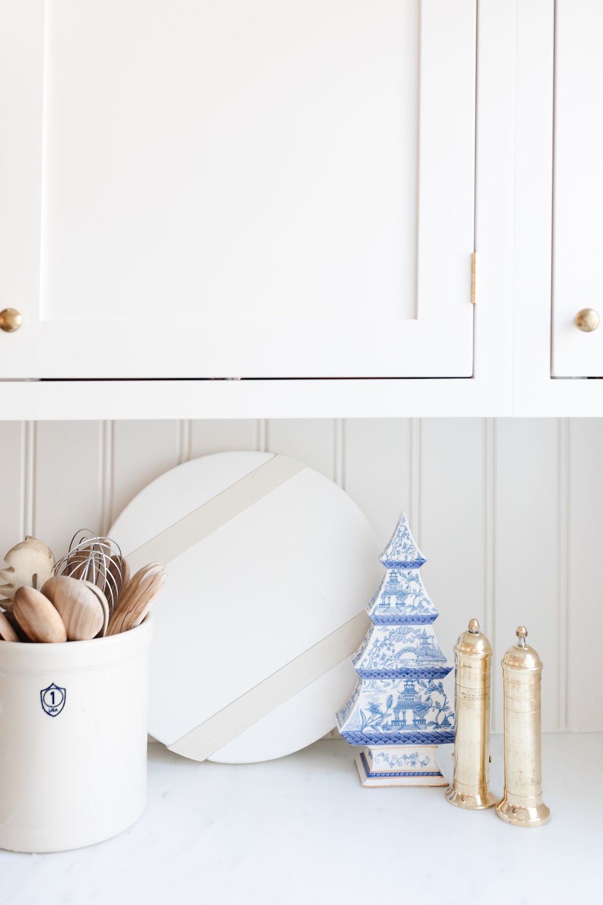 A white kitchen counter with white cabinets and white objects filled with kitchen gifts.