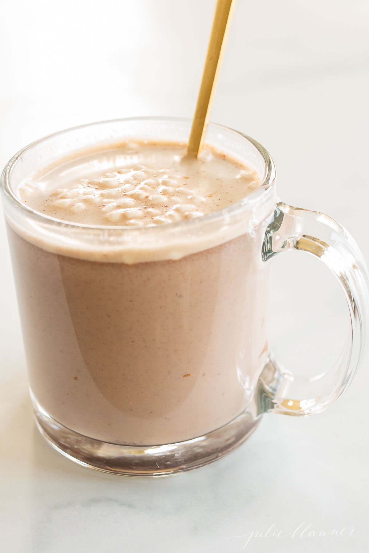 A cup of chocolate milk with a spoon in it.