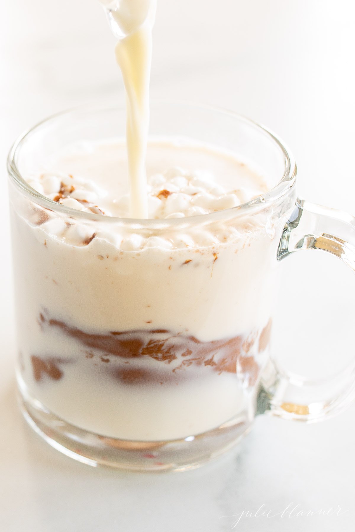 A mug of hot chocolate being poured with milk.