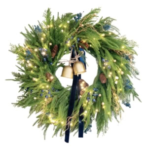 A green norfolk pine garland wreath decorated with pinecones, blue berries, small white ornaments, string lights, and two gold bells hanging in the center with a blue ribbon.