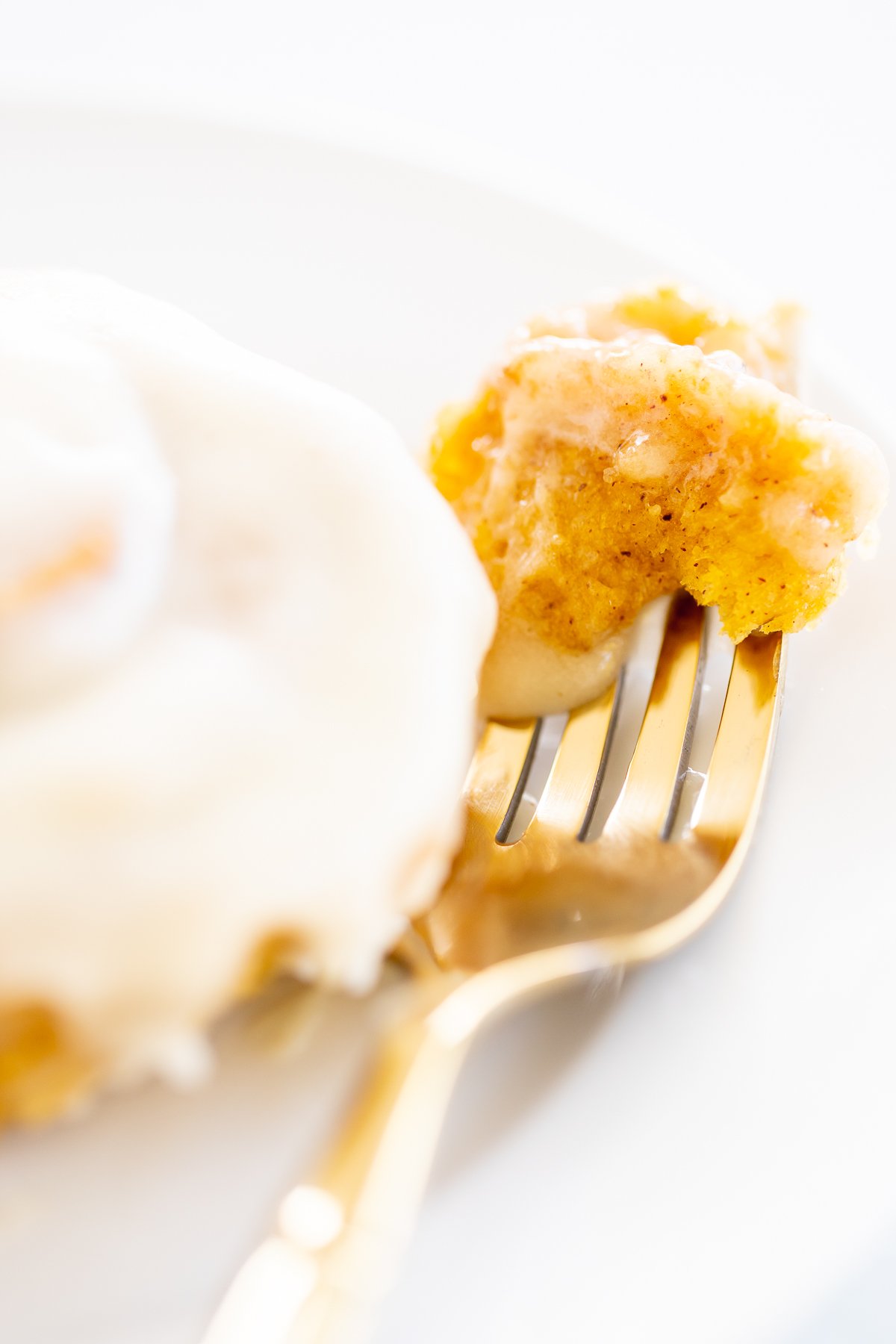 A fork with a piece of pumpkin cinnamon roll on it.