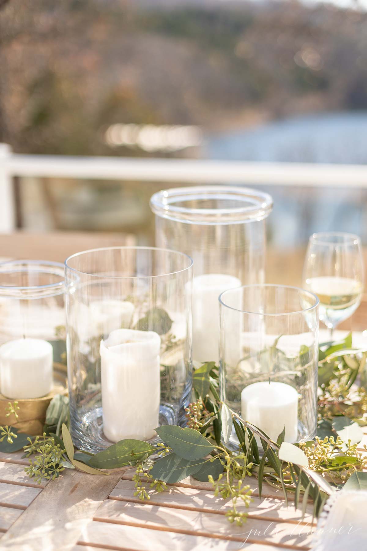 A Thanksgiving table setting adorned with candles and greenery on a wooden table.