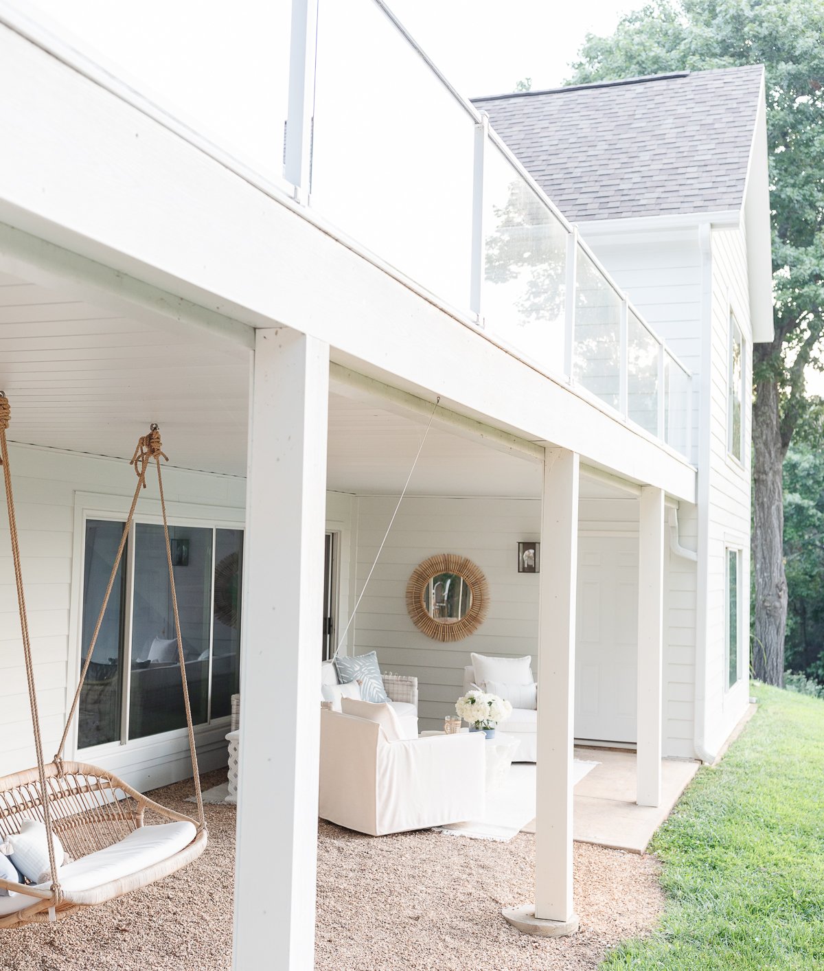 A white porch with a swing and chairs.