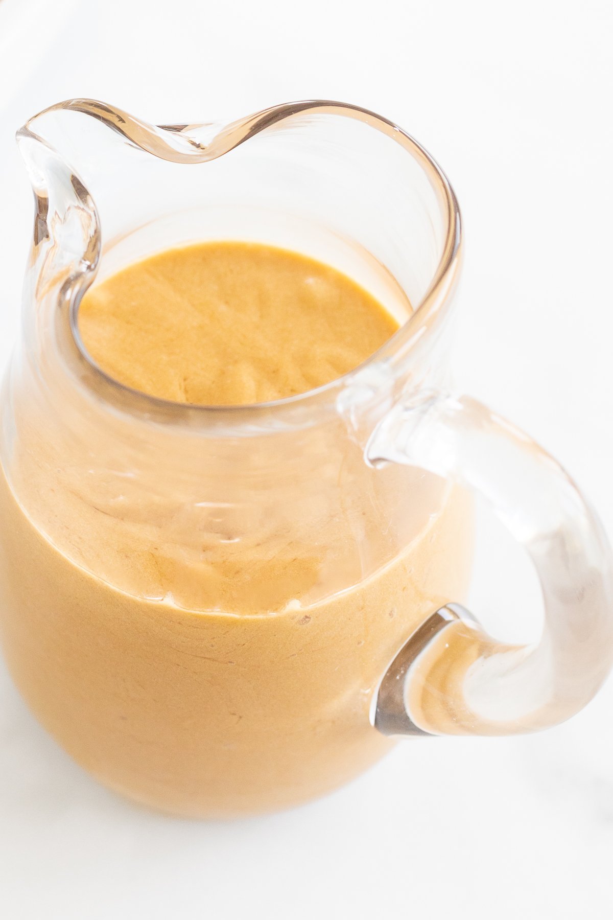 Cookie butter icing in a glass pitcher.