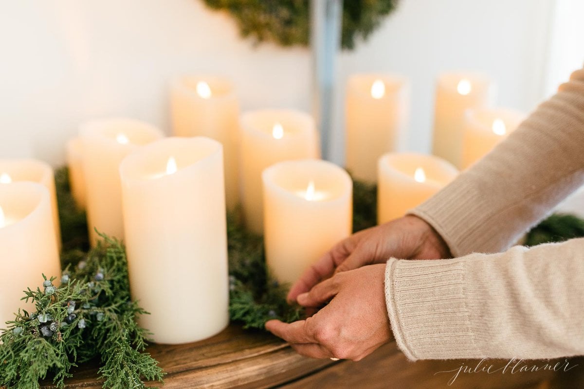 A woman is putting LED candles on a wooden tray.