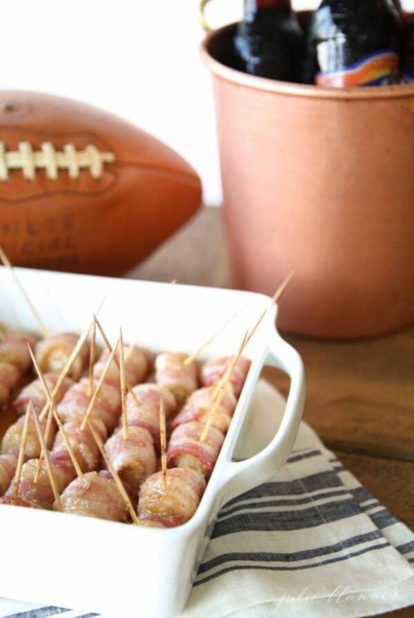 Bacon wrapped pretzels in a dish next to a bottle of beer, the perfect easy chicken appetizer.