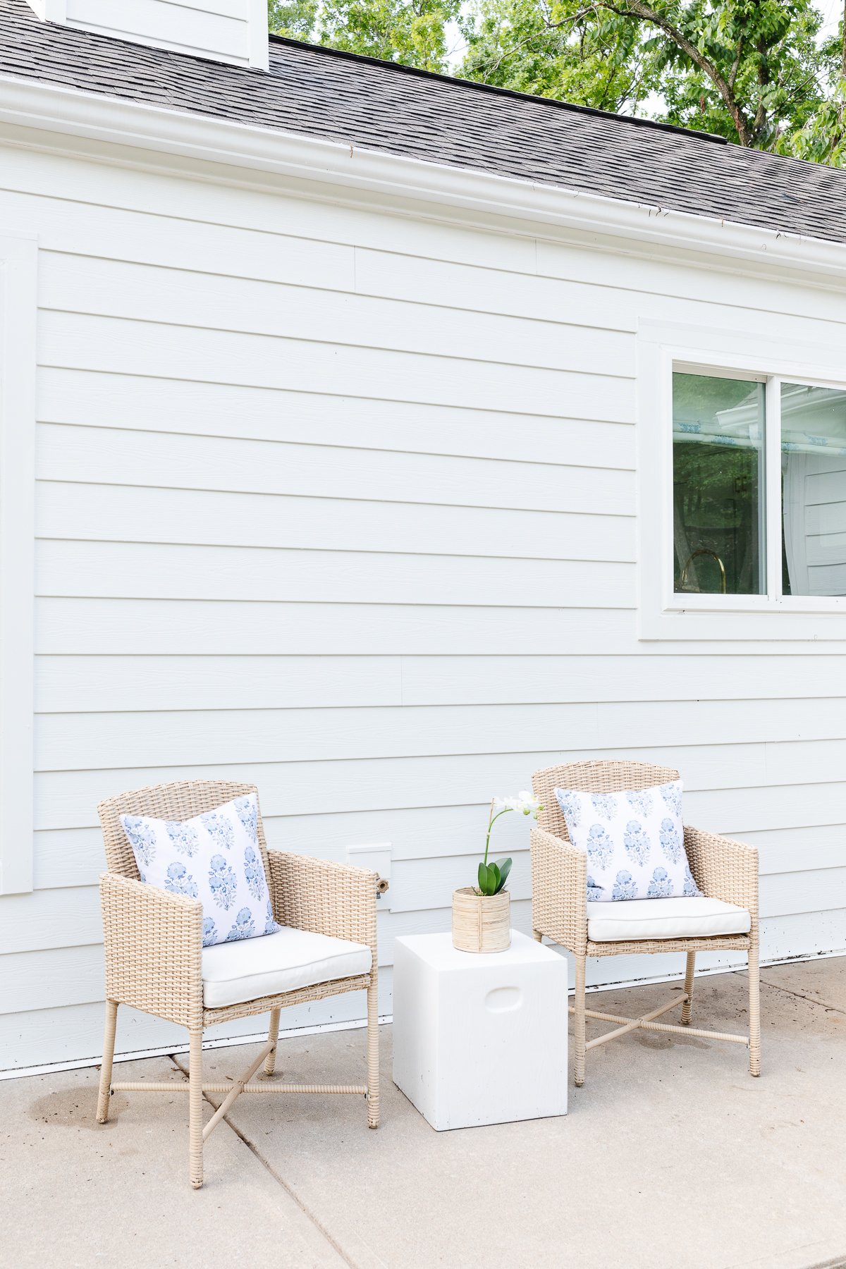 Two wicker chairs in front of an arctic white house.