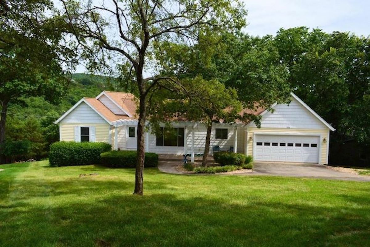 A home with a garage in the middle of a grassy yard.