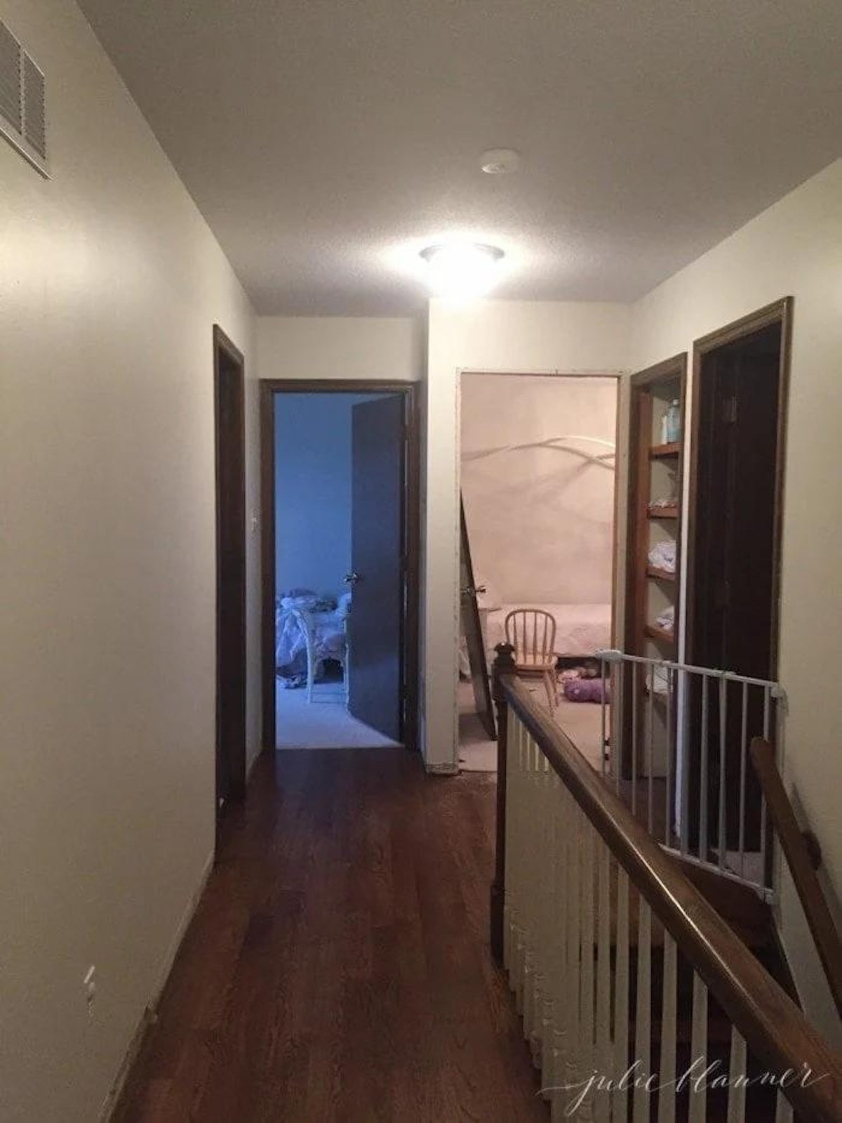 A hallway with hardwood floors and a staircase leading to a room, featuring a linen closet.