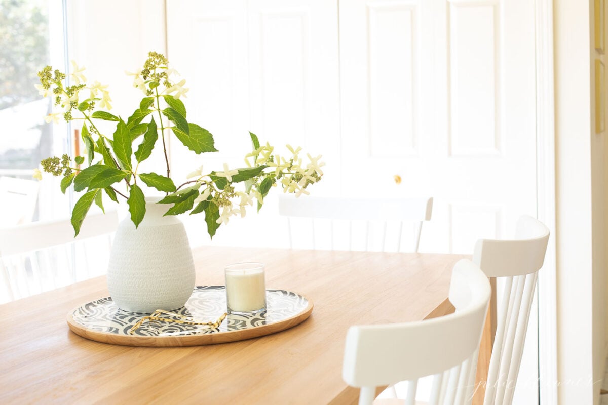 A teak table with a vase of flowers on it.