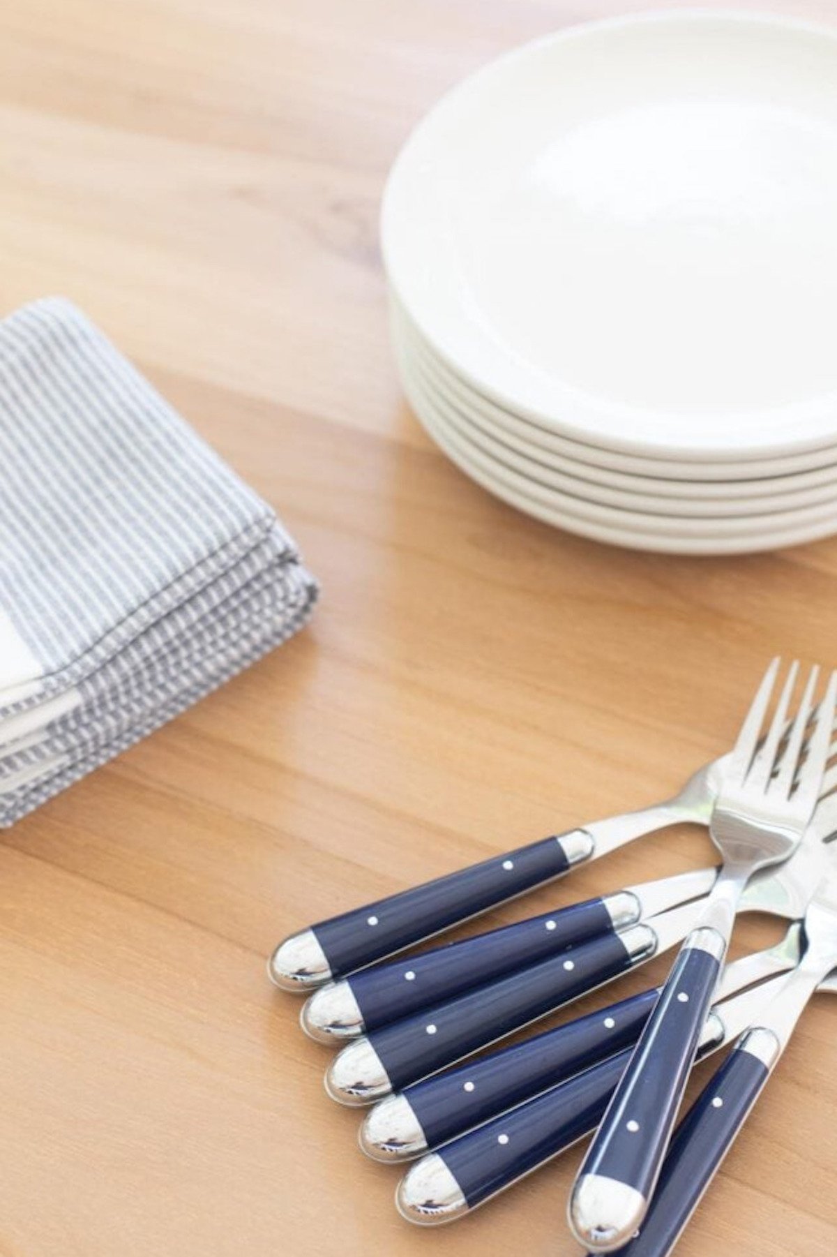 Forks and knives laid out on a teak table.