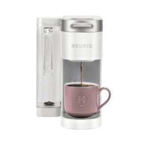 A white Keurig coffee maker sits on a neatly organized kitchen counter, brewing coffee into a pink mug.