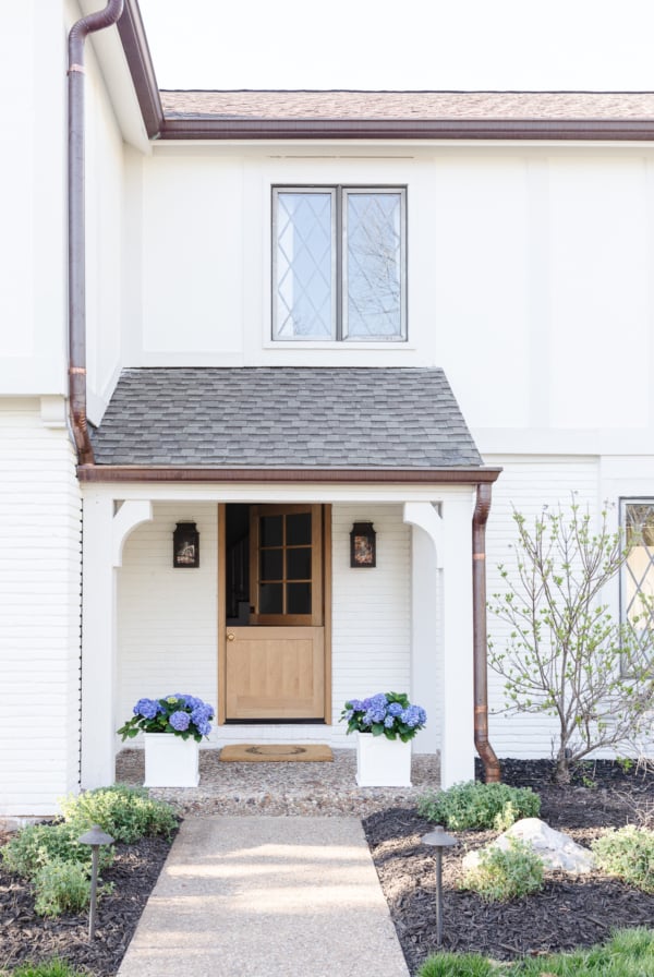 A beautiful white house with a welcoming front porch and charming flower pots.