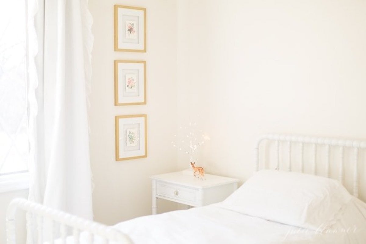 A girl's bedroom with a white bed adorned with framed pictures, exuding Christmas magic.