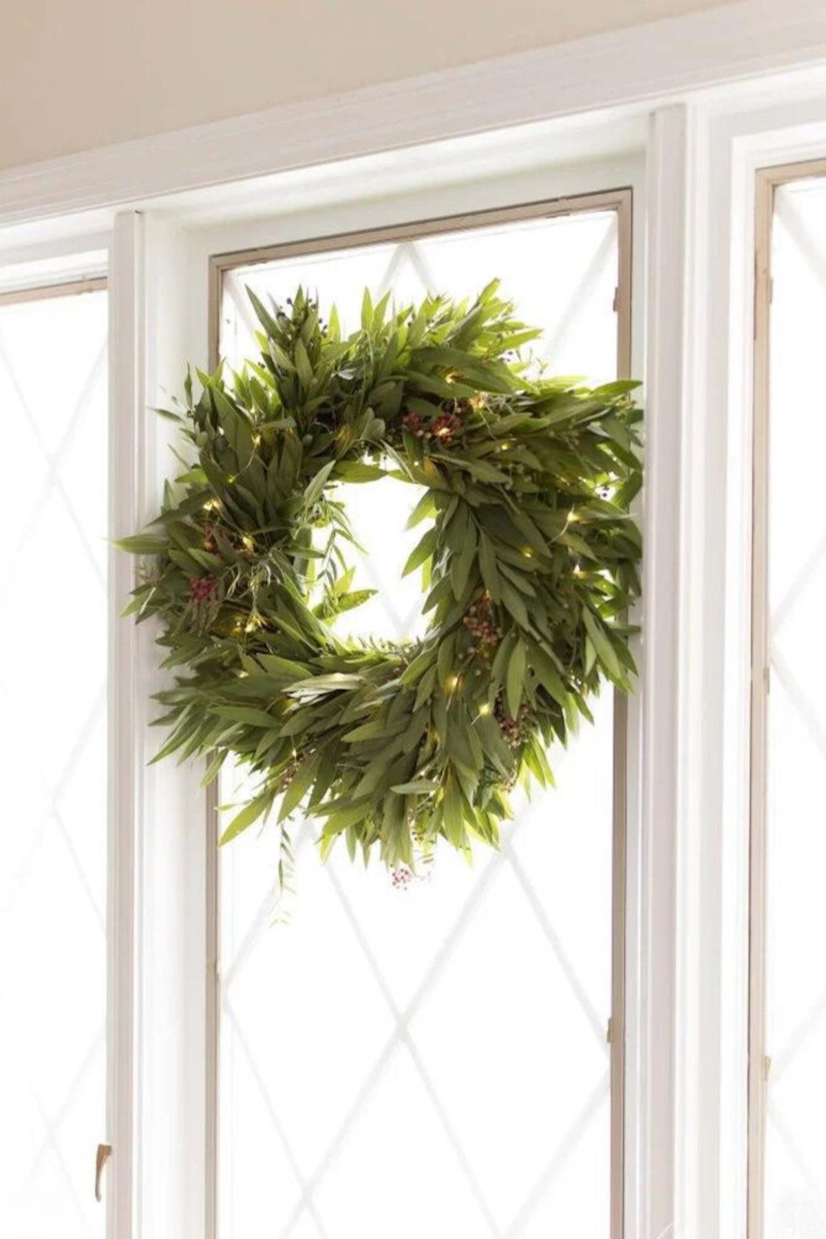 A Christmas wreath hanging on a window sill, exuding holiday magic.
