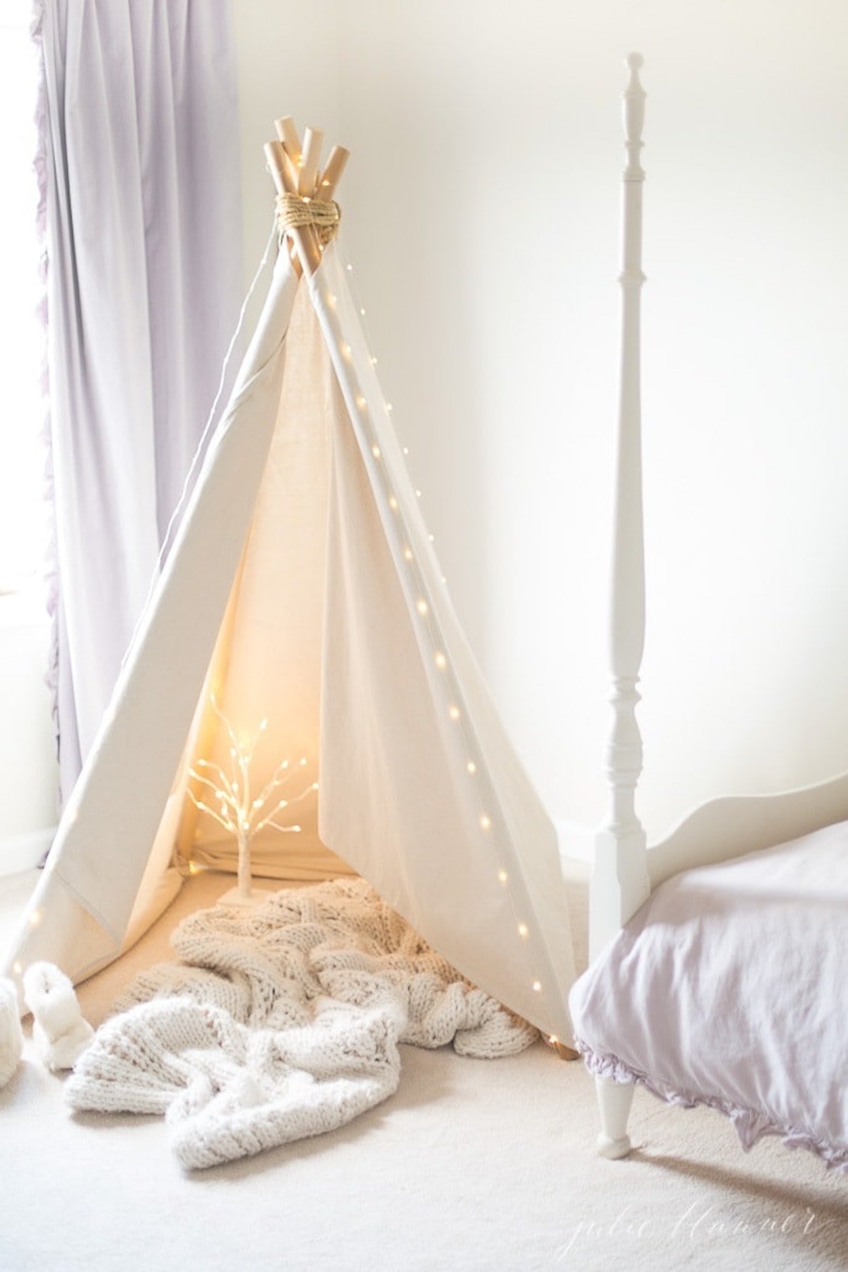 A teepee in a room with a bed adorned with Christmas magic.