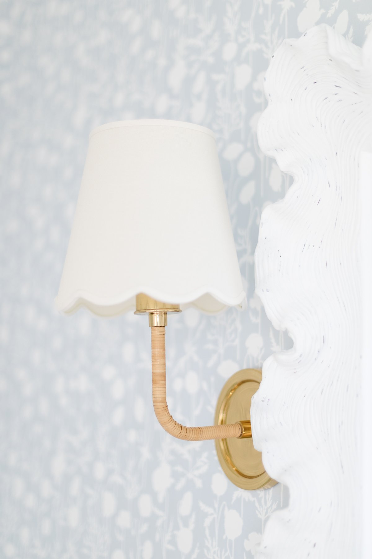 A wall lamp with a white shade on a blue wall.