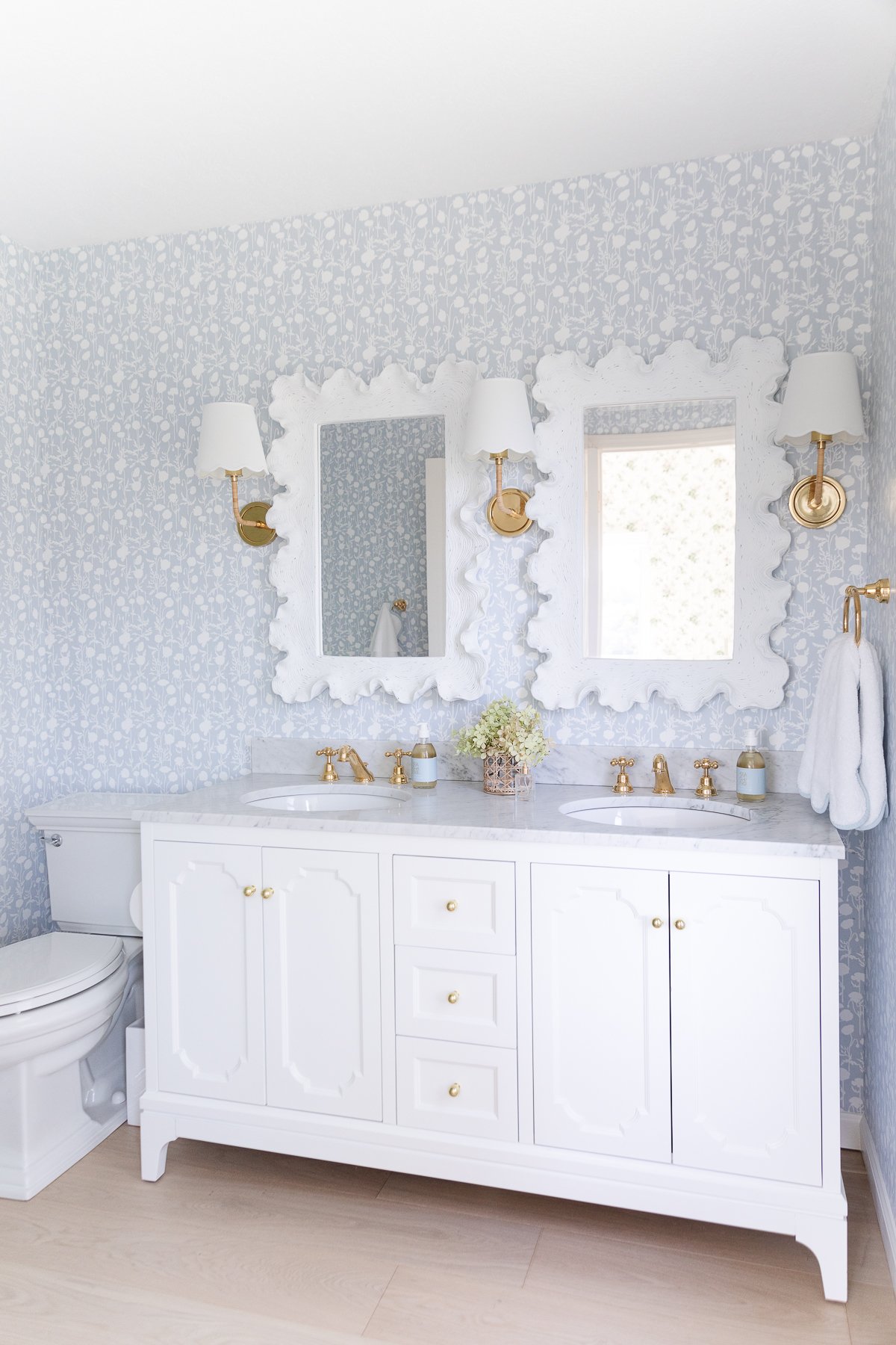 A white bathroom with blue wallpaper.