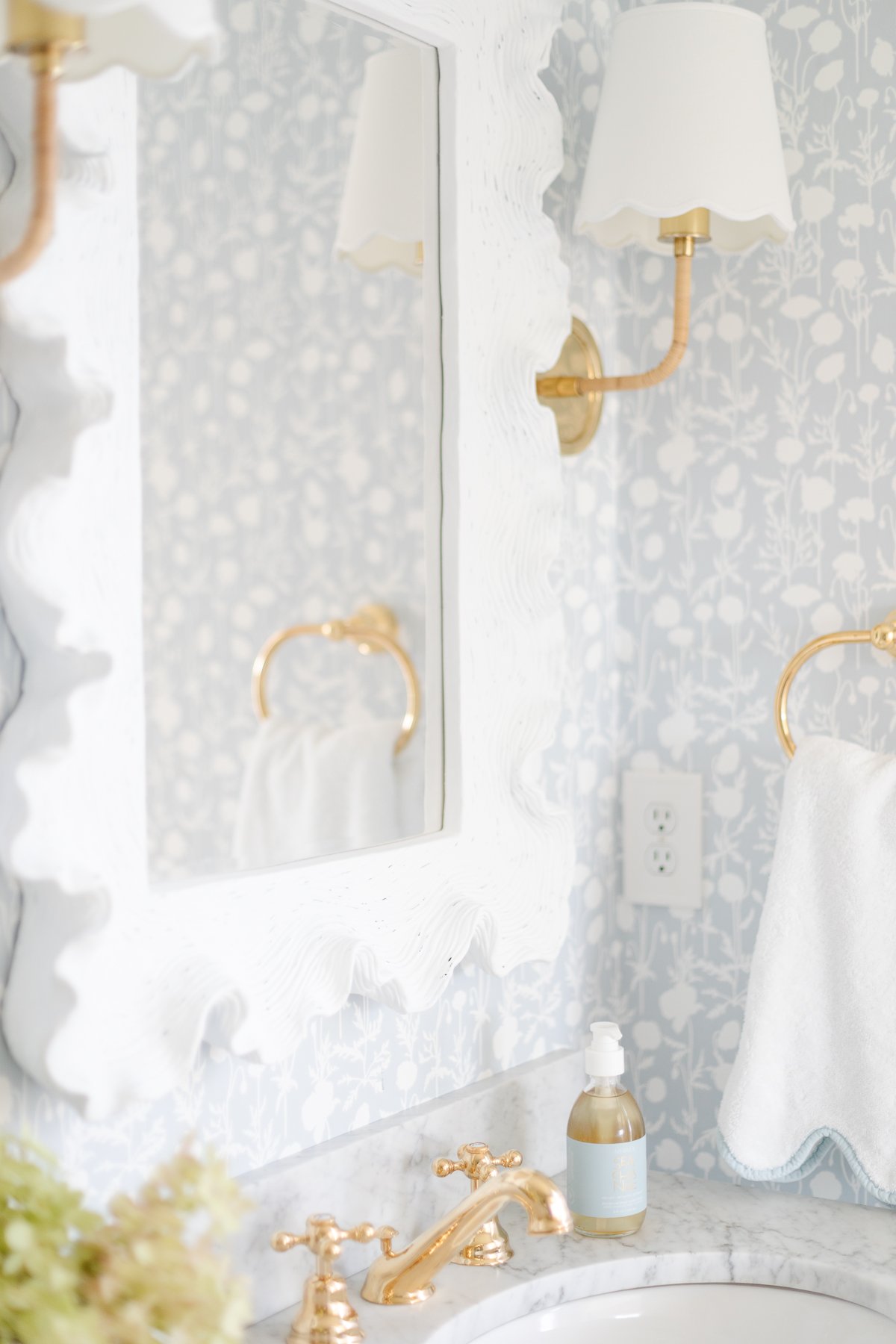 A bathroom with a white sink and a gold mirror.